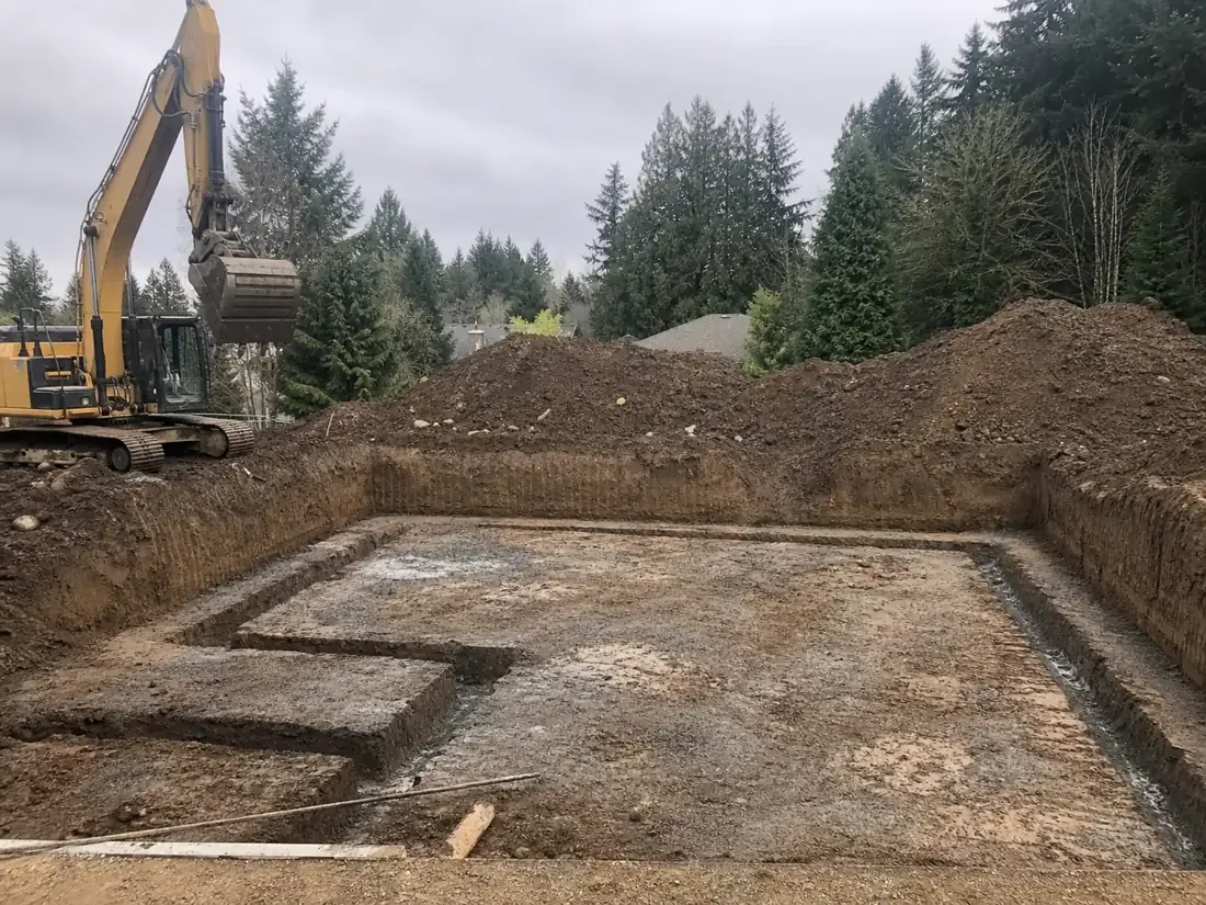 Foundation excavation with squared footing trenches and an excavator in Vancouver, WA