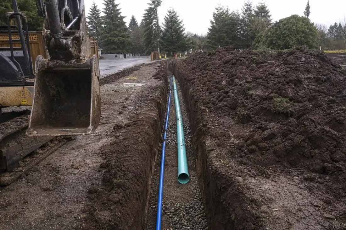 Open utility trench with new water and sewer pipe on gravel bedding in Vancouver, WA
